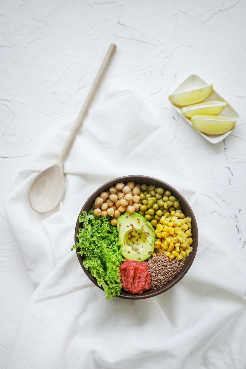 A bowl of greens, chickpeas, corn and avocado on white linen