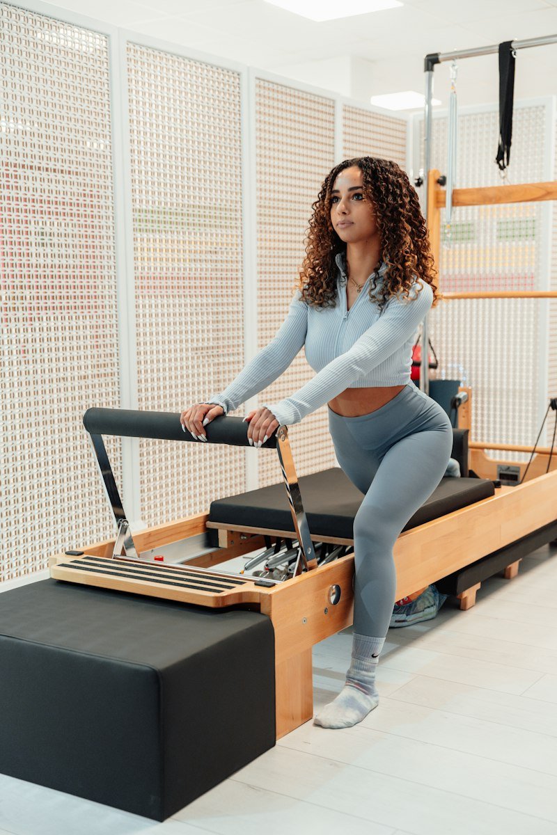A client doing a standing lunge on a reformer, guided through the movement